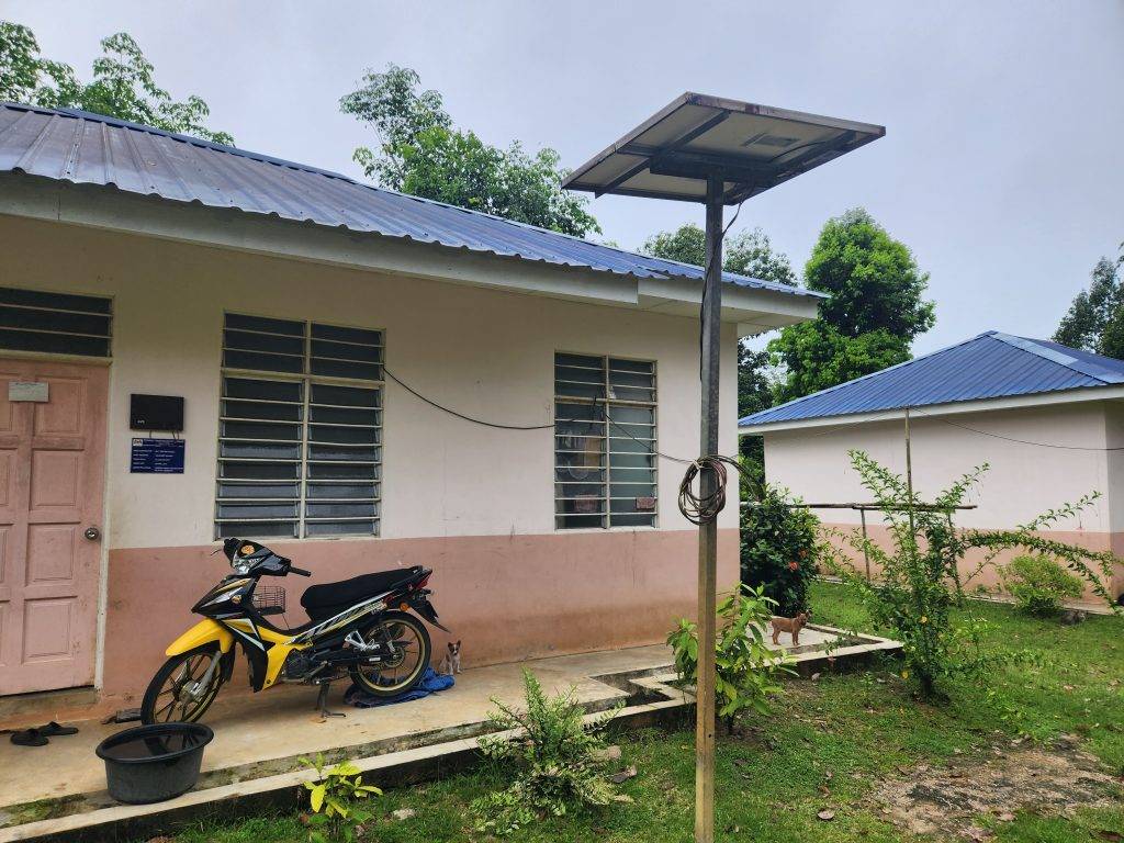 a village house with a motorcycle and a solar panel