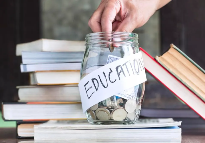 A hand in a glass bottom labelled education with coins inside.